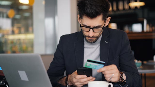 a person making an online payments from the phone while holding a credit card